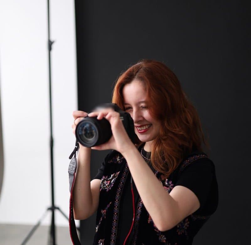 A smiling photographer taking a picture in her studio
